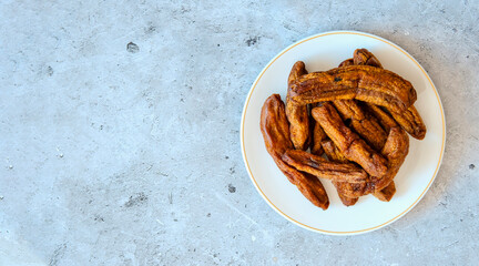 Dried bananas on a white plate on a concrete background