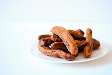Dried bananas on a light plate. Copy space.