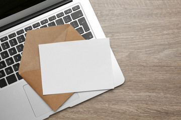 Brown envelope with blank letter and laptop on wooden table, top view. Space for text