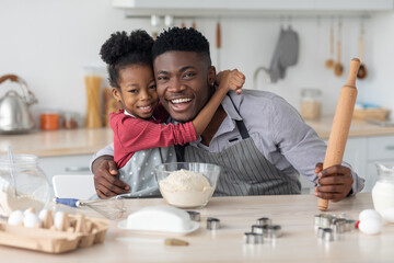 Positive black family making cookies at home