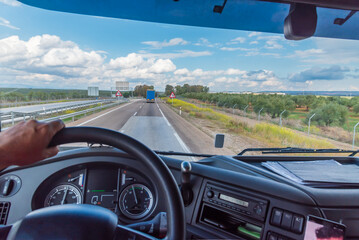 View of the road from the driving position of a truck of a landscape with clouds.
