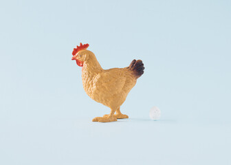 Brown hen and white egg on a pastel blue background. Minimal Easter concept