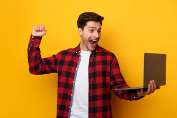 Cheerful young man using laptop gesturing yes