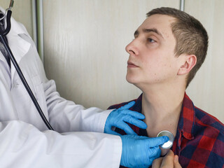 The doctor in the clinic conducts an examination of a man. A phonendoscope listens to heart sounds,...