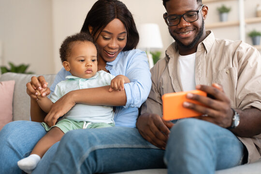 African American family using cellphone with baby at home