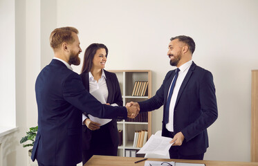 Smiling businesspeople shake hands close deal or make agreement at meeting in office. Happy diverse business partners handshake get acquainted greeting at negotiations. Partnership concept.