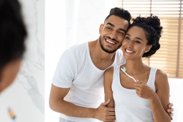 Fototapeta na wymiar Happy Morning. Portrait Of Joyful Young Arab Couple Brushing Teeth In Bathroom