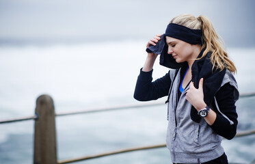 What a workout. Shot of a young woman wiping her forehead with a towel after a run.