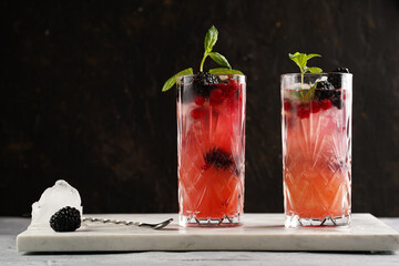 Two long glasses with non-alcoholic mocktail version of the classic blackberry and gin cocktail...