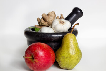 Still life mortar and pestle with apple, pear, garlic and ginger on white background. 