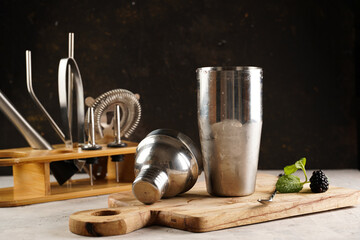 Bartender equipment - cocktail shaker, hawthorne strainer, pourers, bar spoon, muddler , in a bambus stand on wooden board