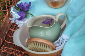 Spa items outdoors in garden in blue and purple colours with jug of water and basin. 
