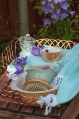 Spa items outdoors in garden in blue and purple colours with jug of water and basin. 