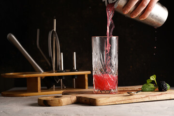 Female bartender hand pouring non-alcoholic mocktail version of the classic blackberry and gin...