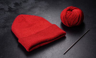 Red warm knitted women's hat on a concrete background