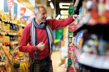 Positive attractive senior man choosing goods at store