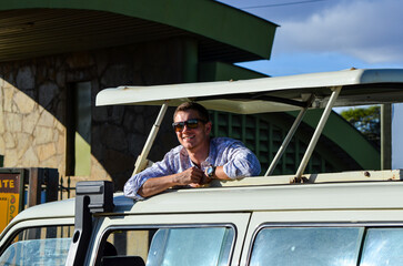 Smiling tourist (man) in sunglasses in a safari car