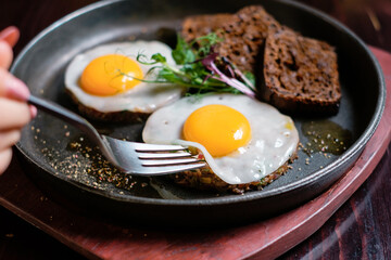 Tasting fried eggs. Eating eggs and tartare with a fork.