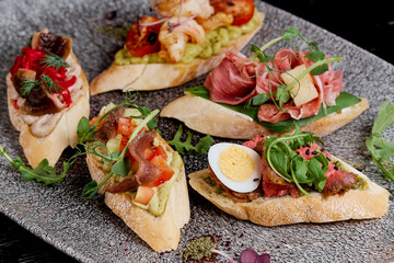 Oval brusquettes with different fillings on a gray oval plate