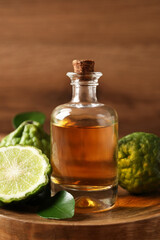 Glass bottle of bergamot essential oil on wooden table - obrazy, fototapety, plakaty