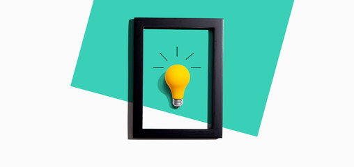 Yellow light bulb inside a frame - inspiration, creativity, energy, electricity themes