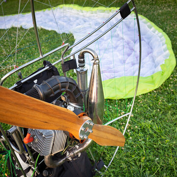 A paraglider with a gasoline engine for flying and a wing in the background. Wing flight preparation. Extreme sports.
