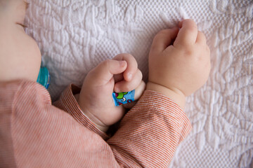 baby with a band-aid on his finger sleeps peacefully in his bed