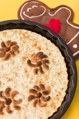 top view of a large round cottage cheese casserole with whole cashews and hazelnuts on a yellow background
