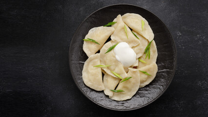 Boiled Ukrainian dumplings on a dark background, with space for text