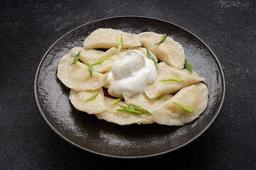 Boiled Ukrainian dumplings on a dark background, with space for text