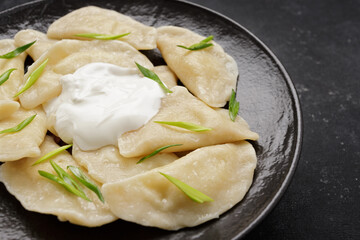 Boiled Ukrainian dumplings on a dark background, with space for text
