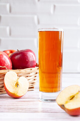 Red raw apple in basket with glass of apple juce. Simple composition. Box with apple before white wall. The half of apple. Selective focus.