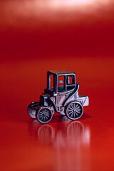 Stylish miniature car model, on a red background. A toy made of metal, covered with chrome, a miniature car model, silver color.