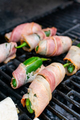 chiles jalapeños rellenos de queso y chorizo envueltos en tocino. chiles jalapeños manos preparando chiles jalapeños en el asador.	