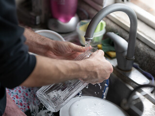 manos masculinas lavando jarra de vidrio con esponja amarilla 