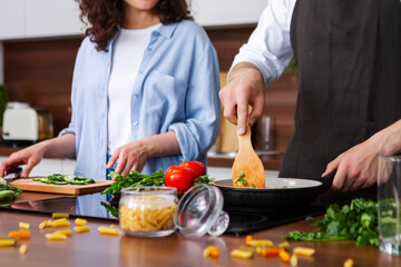 Closeup female and male hands are cooking dishes in kitchen. Young couple in love spends their leisure time together at home. Quarantine mood. Stay at home. Relationships between woman and man.
