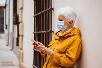 .Middle-aged woman enjoying the new normal outdoors. Wearing a mask while making a call with her...
