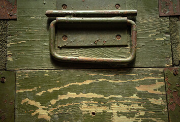 Photo of the texture of a green military wooden box with a metal handle. Military arsenal.