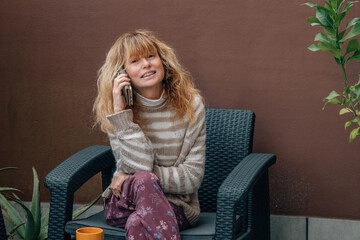 Obraz premium middle-aged woman on the terrace of a house talking on a mobile phone or smartphone