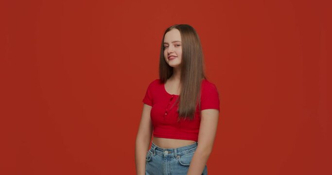Modern playful beautiful young girl flirting, smiling, wink, hinting, posing on orange background. Copy space for ad