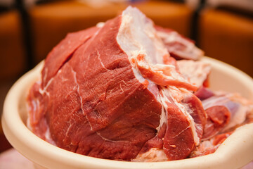 A large piece of raw meat cut into the shape of a square. Fresh beef. Preparation for cooking.