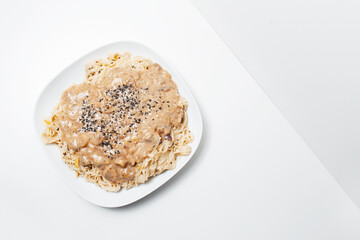 Vegan food. Top view of homemade fettuccine pasta with Alfredo sauce, on white.