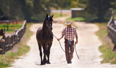 Lets go for a talk. Shot of a cowboy leading his horse by the reins.