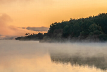 Fog rising from a still river at dawn, yellow and orange skies, nobody