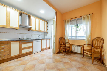 Kitchen with conventional wooden decoration and rustic stoneware floors with wooden chairs in the office