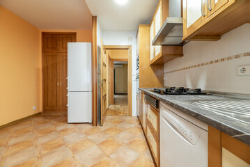 Kitchen with conventional decoration in wood and rustic stoneware floors with gray countertop, white appliances and wooden furniture