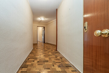 Entrance door to a residential house with long hallway with oak floorboards