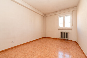 empty room with orange stoneware floors, wrought iron radiator and white aluminum window