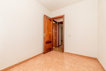 empty room with orange stoneware floor, mahogany wood door and white painted walls