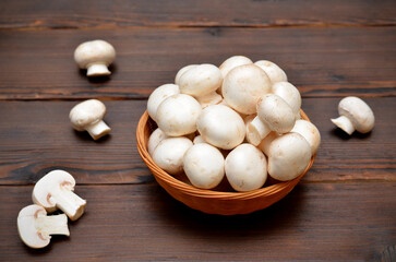 champignons in a basket and mushrooms on the wooden table